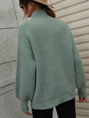 Green ribbed knit turtleneck sweater with voluminous balloon sleeves.