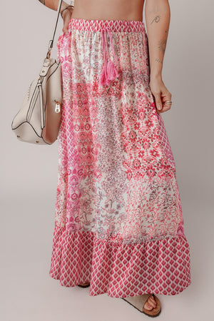 Printed tiered maxi skirt in dusty pink with tassel detail and boho pattern.