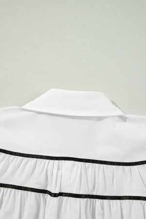 White blouse with black piped trim and ruffled tiers