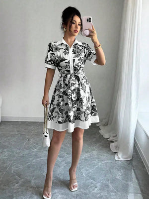 Black floral print mini dress with short sleeves, collar, and tie belt.