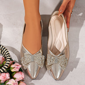 Gold pointed toe flats with dazzling crystal bows.