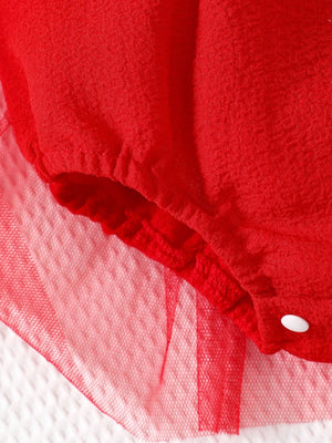 Red baby bodysuit dress with smocked waist and tulle trim detail.
