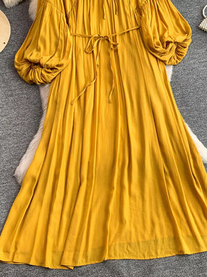 Yellow bohemian maxi dress with balloon sleeves, drawstring waist, and tie neckline.
