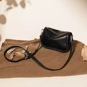 Sleek black leather crossbody bag with adjustable strap and silver zipper detail.