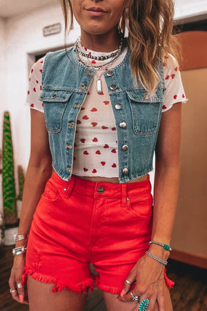 Sheer white t-shirt with red hearts, cropped short sleeves, layered under a denim vest.