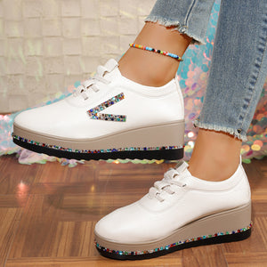 White wedge sneakers with rhinestone embellishments on the side and sole.