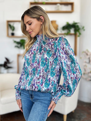 High neck abstract print blouse in blue and red-violet with long sleeves and smocked cuffs.