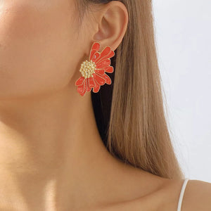 Textured orange flower stud earrings with gold center detail.