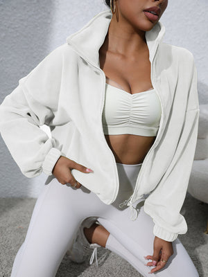 White fleece cropped jacket with funnel neck and zipper closure, styled with a sports bra.