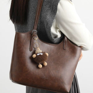 Brown pu leather tote bag with a fuzzy charm and adjustable strap