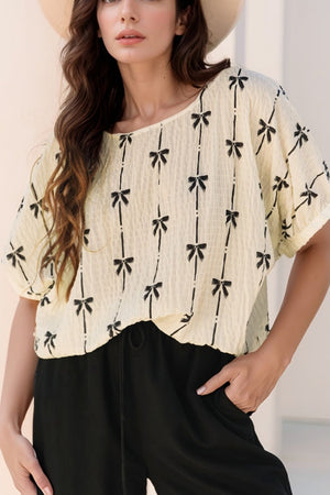 Beige gauze blouse with black bow print and gathered sleeves.
