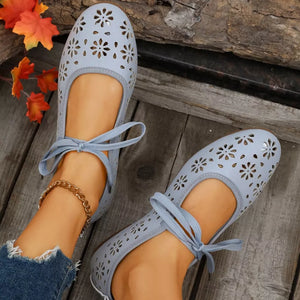 Sky blue floral cutout slip-on flats with ankle ties and a gold anklet.