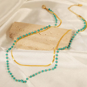 Gold layered necklace with turquoise beads and a flat serpentine chain.