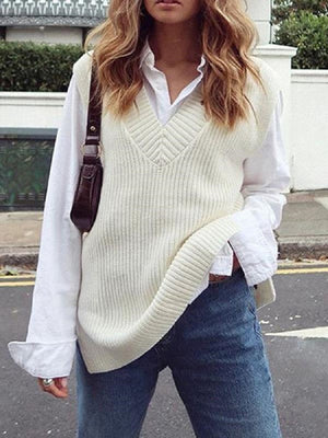 Cream textured knit vest with V-neck and asymmetric hem, styled over a white shirt.