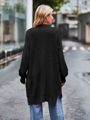 Black open-stitch waffle knit duster cardigan with side slits and long sleeves.