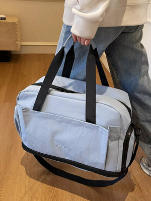 Light blue Oxford cloth travel tote bag with black trim and straps, front pocket detail.