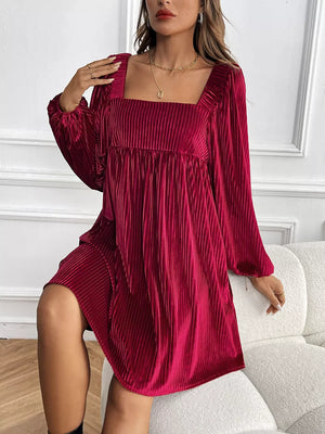 Velvet mini dress with square neckline, long sleeves, and vertical pleats.