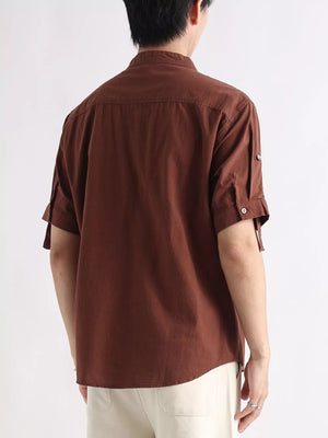 Brown cotton button-down shirt with rolled-up sleeves and button detail.