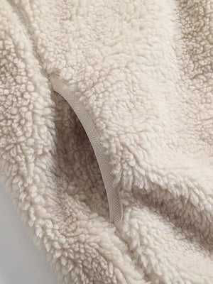 Beige sherpa zip-up jacket with chevron trim pocket detail.