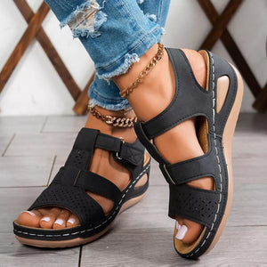 Black perforated mid-wedge sandals with adjustable straps and white stitching detail.