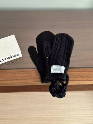 Black cable knit acrylic mittens with braided detail and a loop.