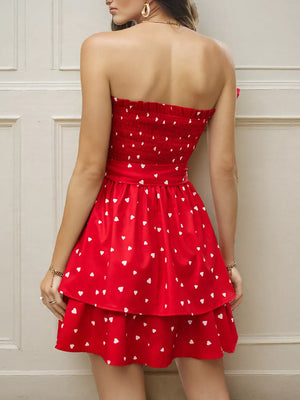 Red smocked strapless mini dress with white hearts, tiered skirt, and bow detail.