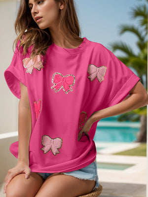 Hot pink oversized tee with sequin bow embellishments and rolled sleeves.