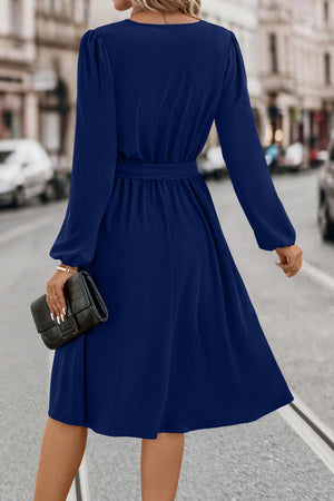 Navy midi dress with poet sleeves, V-neck, and tie waist.