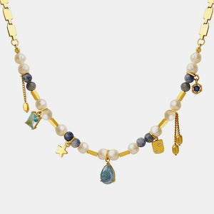 Gold charm necklace with pearls, blue stones, and celestial charms.