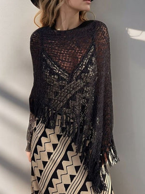 Black open-knit boat neck poncho with fringe trim, acrylic, worn over a patterned dress.