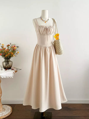 Elegant square neck A-line maxi dress in beige with tie detail and gathered bodice.