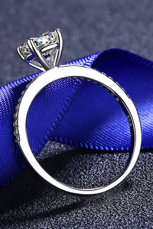 Sparkling moissanite ring in silver with pave band detail on blue ribbon.