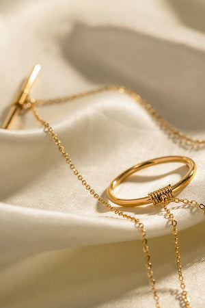 Gold double-layered geometric pendant necklace with toggle clasp and oval charm wrapped in wire.