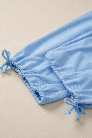 Light blue knit jogger pants with drawstring cuffs and textured fabric detail.
