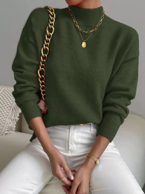 Army green mock neck sweater with dropped shoulders, paired with white jeans.