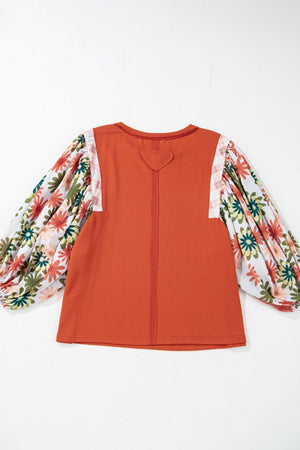 Orange-red blouse with floral patchwork balloon sleeves and a heart detail at the back neckline.
