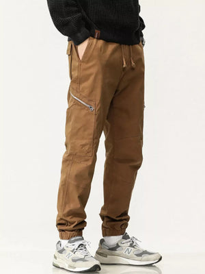 Men's caramel cotton cargo pants with zipper pockets and drawstring waist.