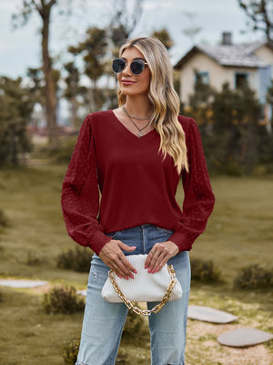 Burgundy V-neck blouse with Swiss dot textured sleeves and long sleeves.