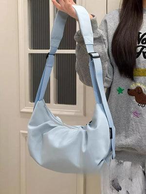 Light blue crescent shape crossbody bag with adjustable strap and zipper closure.