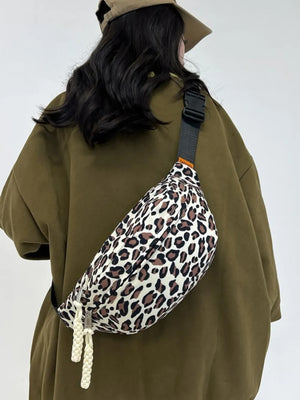 Pleated leopard print sling bag with white braided zipper pulls.