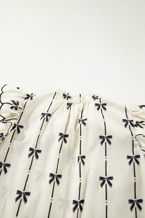 Ivory blouse with black bow print, ruffled sleeves, and a gathered neckline.
