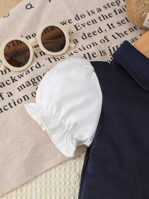 Navy polo dress with white ruffled short sleeves and a collared neckline.
