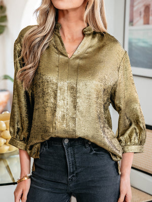 Gold textured blouse with 3/4 sleeves and notched V-neck, styled with dark wash jeans.