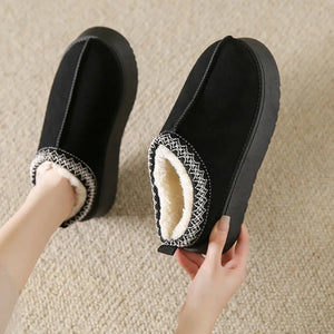 Black shearling trim platform mules with white embroidered detail and plush lining.