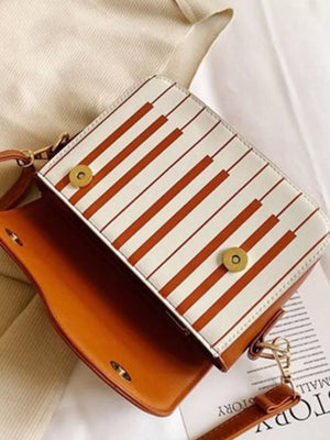Melodic piano key crossbody bag in brown with white and orange stripe flap detail.