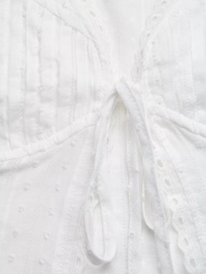 White lace-trimmed tie-front maternity blouse with textured fabric and eyelet details.