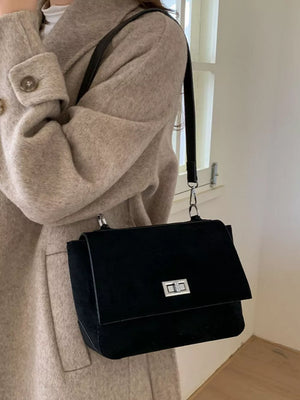 Sleek black suede crossbody bag with silver turn-lock closure and flap.