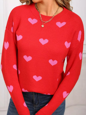 Red acrylic sweater with pink heart print and crew neck.