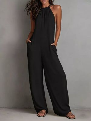 Black halter neck wide leg romper with pockets, styled with sandals.