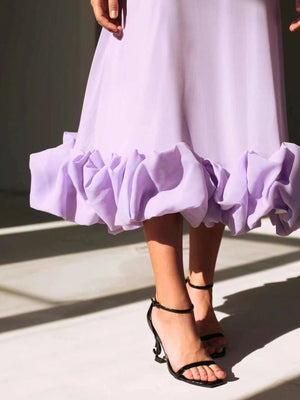 Lavender midi dress with a dramatic ruffle hem, shown with black heeled sandals.